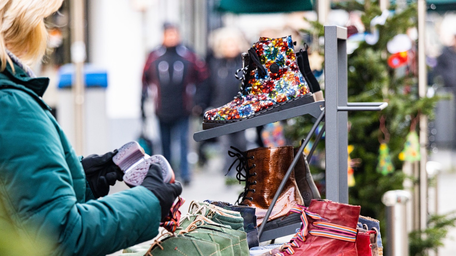 Beim gut besuchten verkaufsoffenen Sonntag am dritten Adventswochenende in Rheinbach schaut sich eine Frau verschiedene Stiefel an.