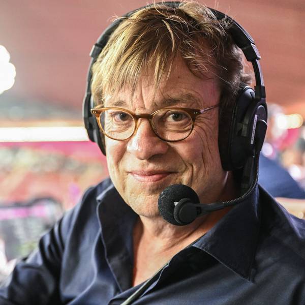 Fußball-Kommentator Béla Réthy sitzt vor einer Übertragung der Fußball-Weltmeisterschaft 2022 in Katar im Stadion an seinem Kommentatorenplatz. Er trägt ein Headset mit Mikrofon.