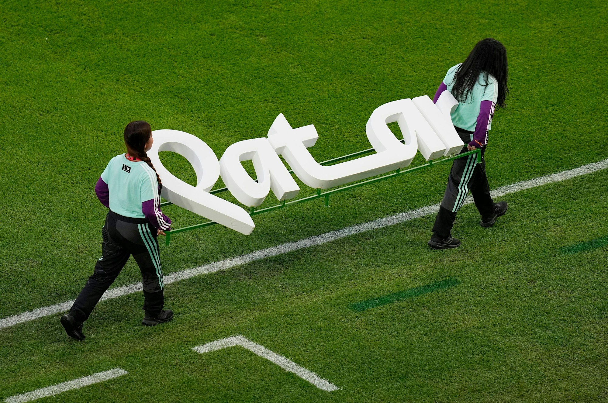 Helfer tragen den Schriftzug von Katar vor einem Spiel der Fußball-WM (Symbolbild).