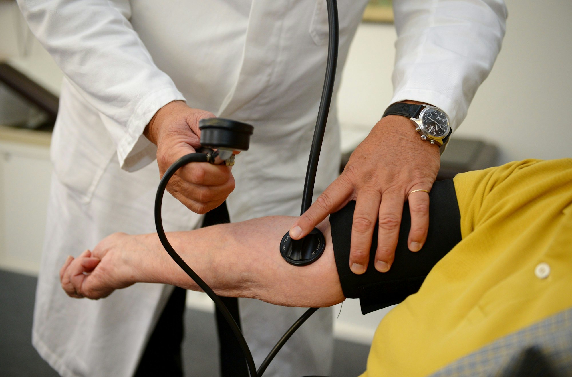 Ein Hausarzt misst in seiner Praxis einer Patientin den Blutdruck.