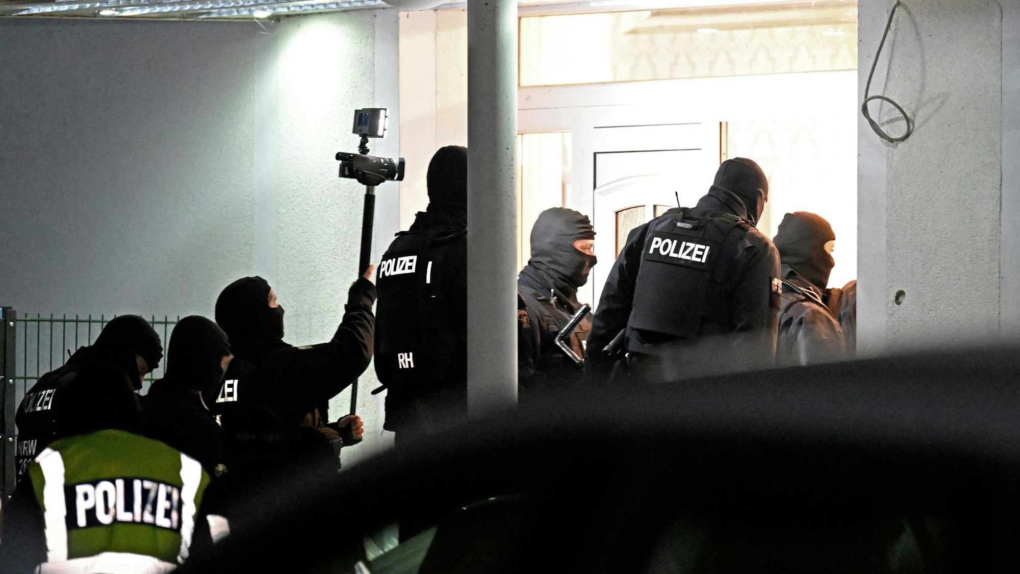 Vermummte Polizisten bei der Razzia vor einem Haus.
