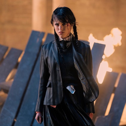 Jenna Ortega steht in einer Serienszene vor einem brennenden Bretterhaufen.