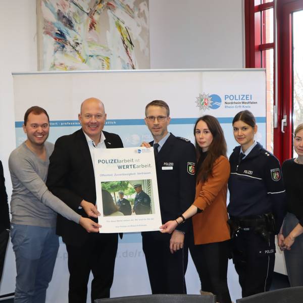 Landrat Frank Rock und Michael Stettien vom Leitungsstab der Polizei (M.) und weitere Personen halten ein Plakat in die Höhe.