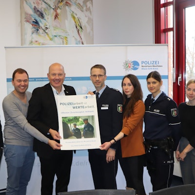 Landrat Frank Rock und Michael Stettien vom Leitungsstab der Polizei (M.) und weitere Personen halten ein Plakat in die Höhe.