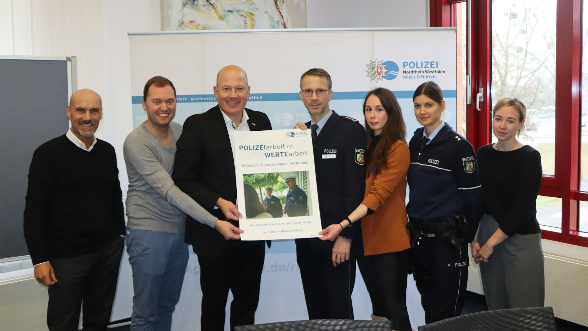 Landrat Frank Rock und Michael Stettien vom Leitungsstab der Polizei (M.) und weitere Personen halten ein Plakat in die Höhe.