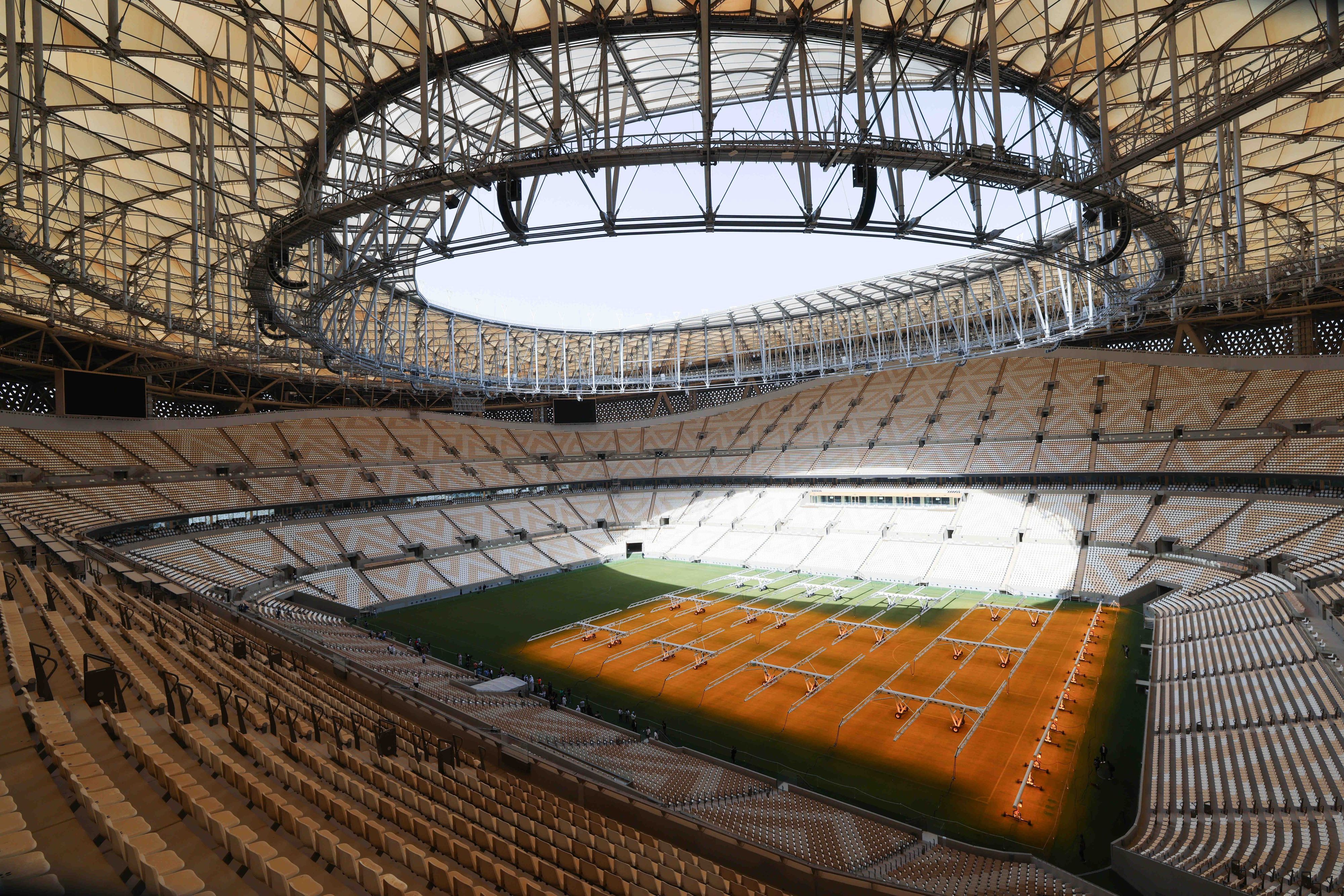 Zu sehen ist das Innere des Fußballstadions, von oben aus einer Tribüne fotografiert. Es ist Tag und die Sonne scheint in das Stadion.