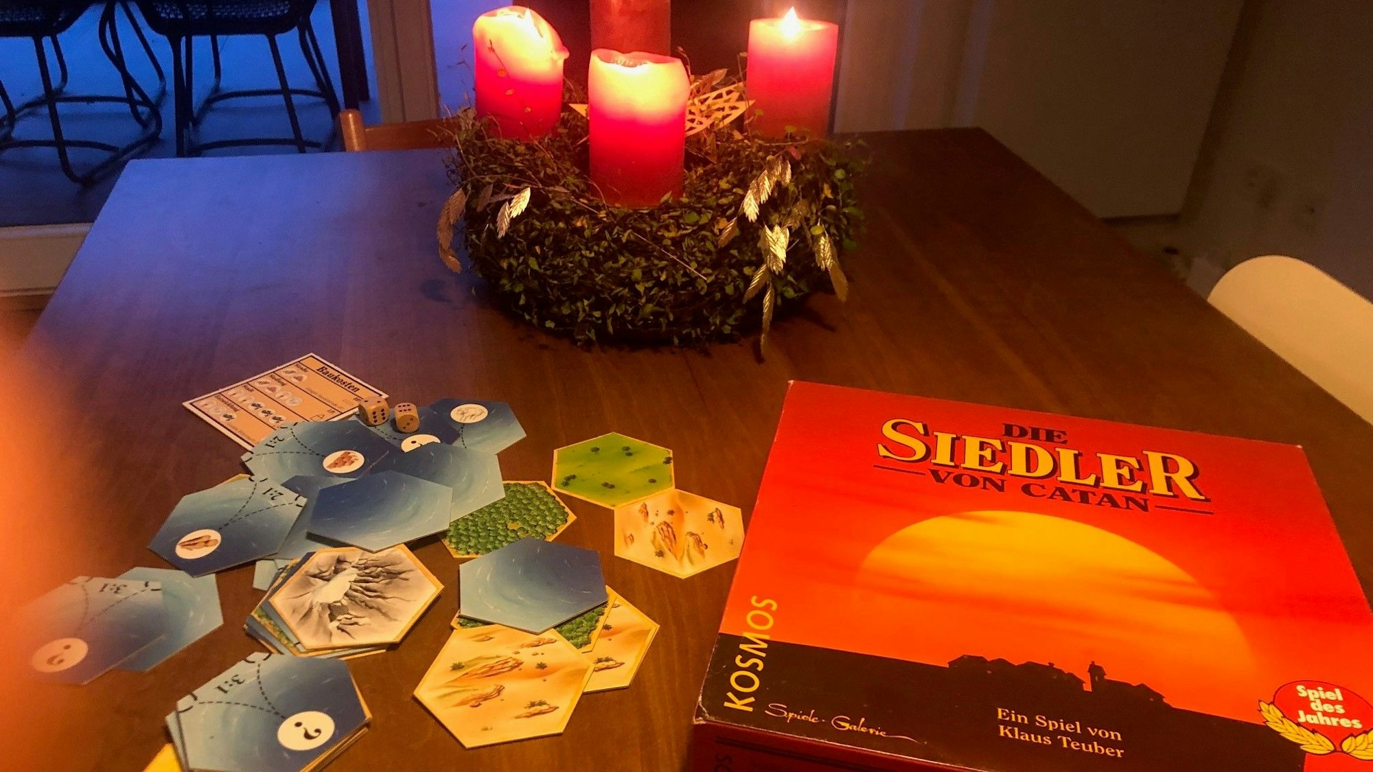 Das Spiel die Siedler von Catan auf einem Tisch mit Adventskranz.