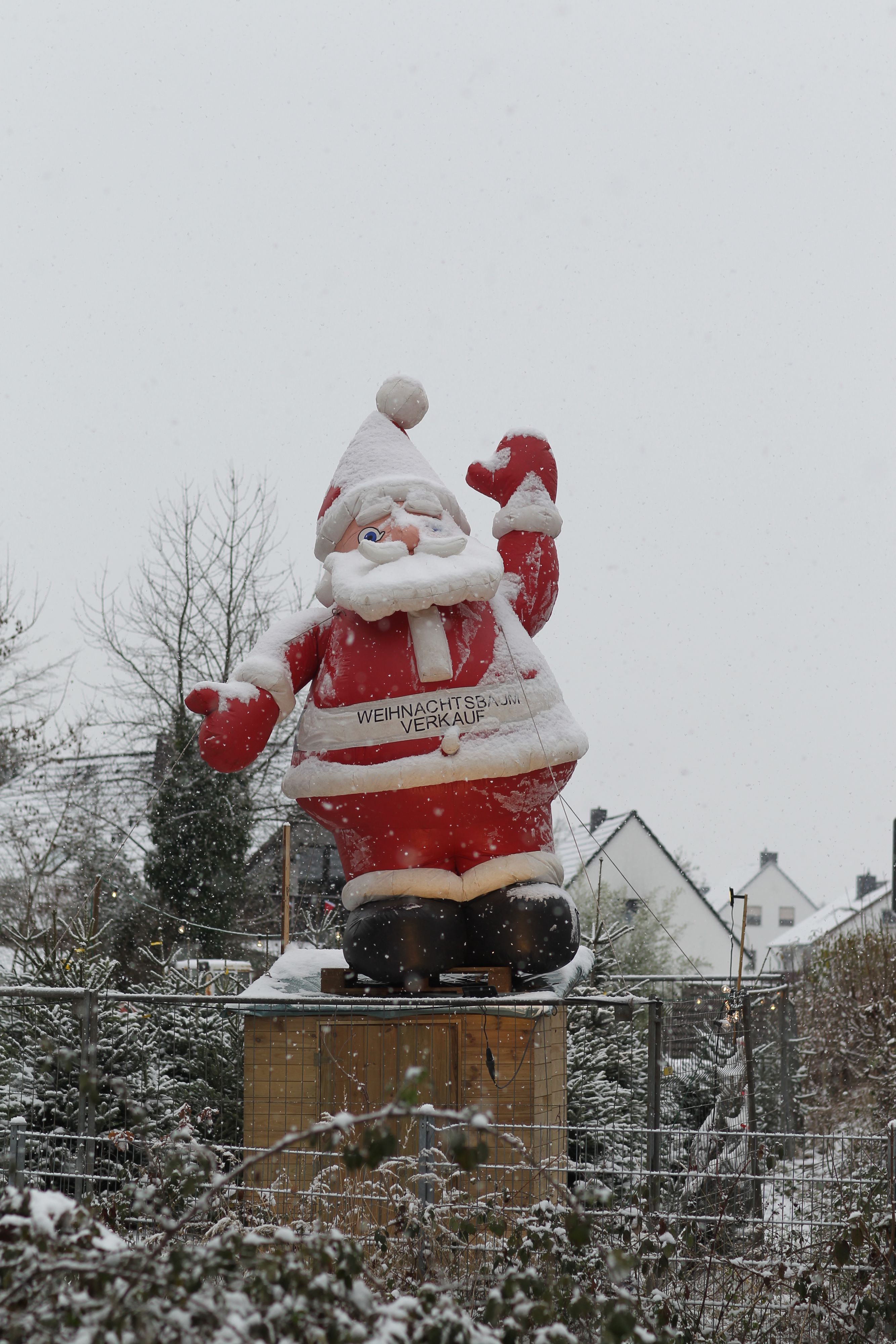 Eine Weihnachtsmannfigur steht in Siegburg im Schneefall.