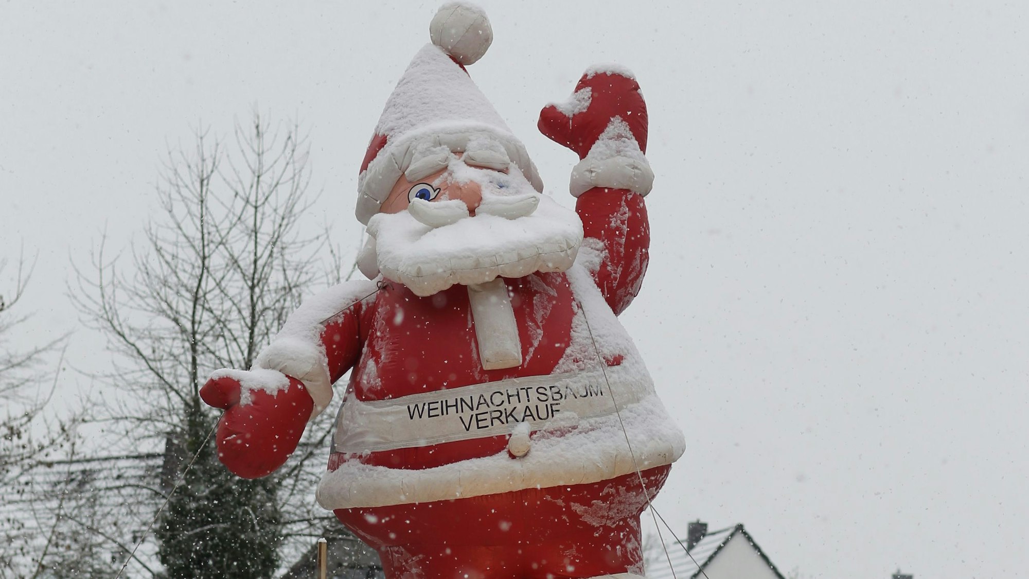Eine Weihnachtsmannfigur steht in Siegburg im Schneefall.