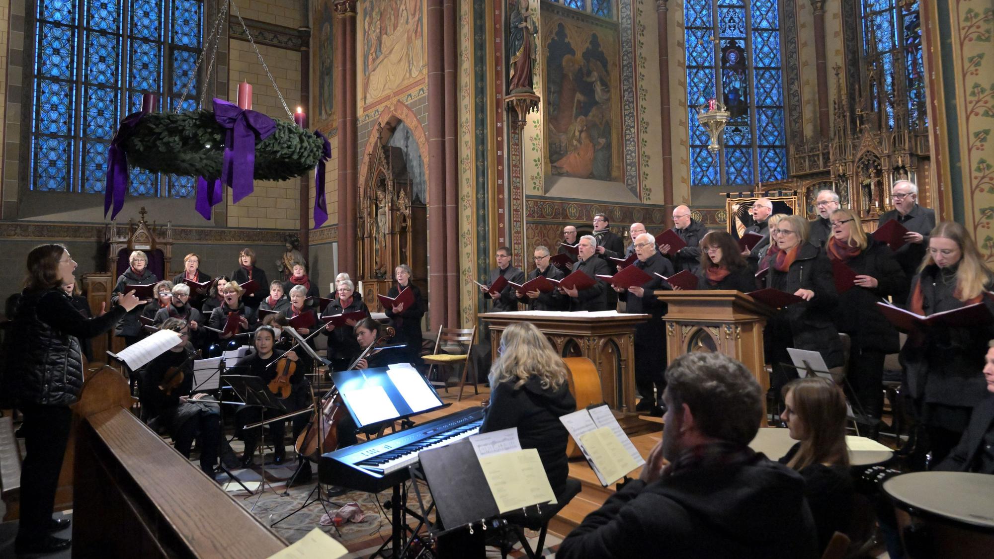 Im Altarraum der Olper Kirchen singen die Sängerinnen und Sänger des Pfarrcäcilienchores Olpes, vor dem Chor sitzen die Instrumentalisten.