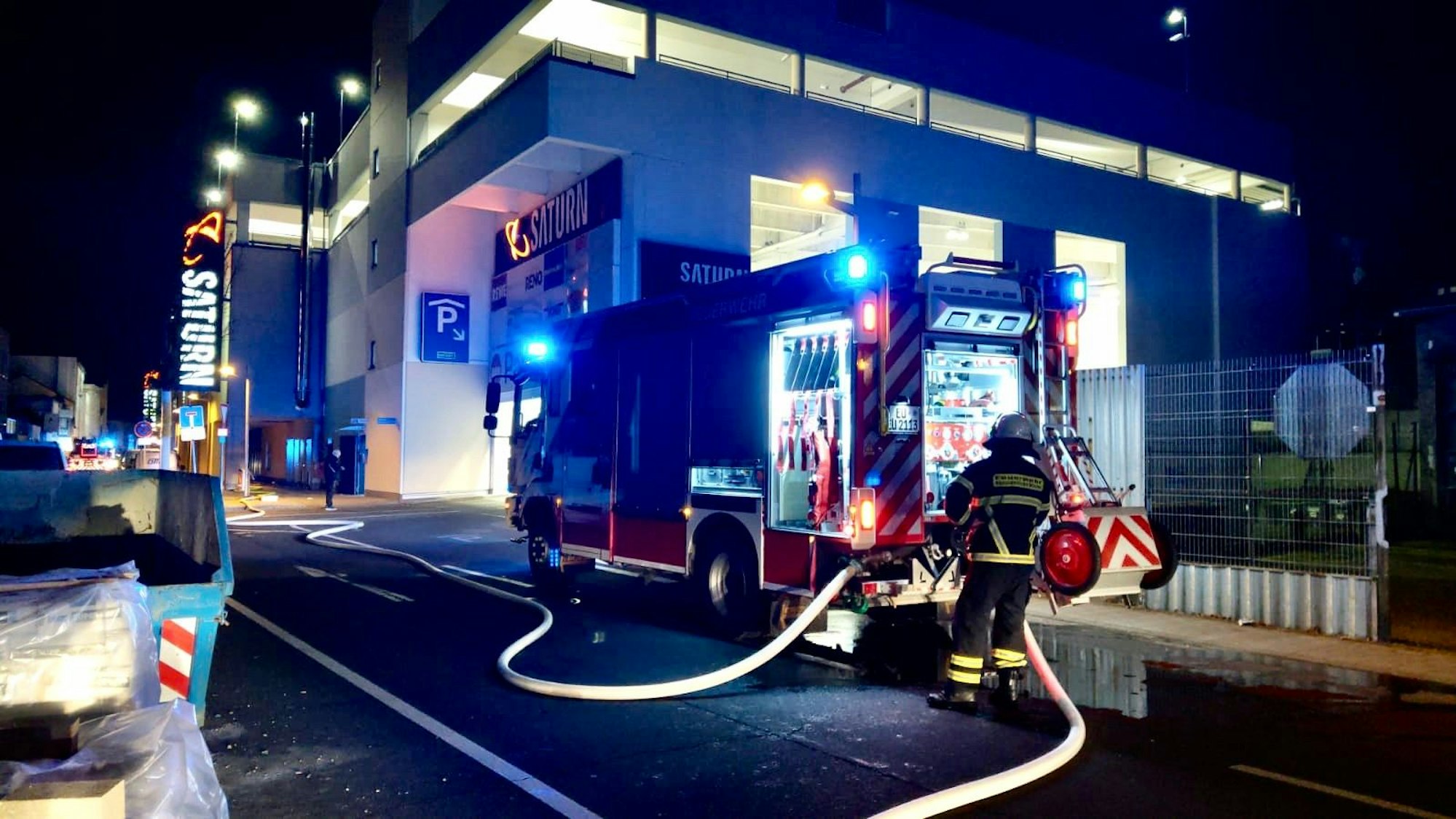 Ein Feuerwehrmann steht an einem Löschfahrzeug vor dem Veybach-Center.