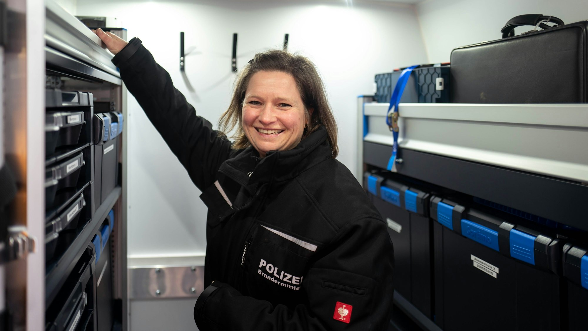 Die Brandermittlerin Jessica Scheer-Thielen steht in dem neuen Brandmobil und greift in ein Regal.