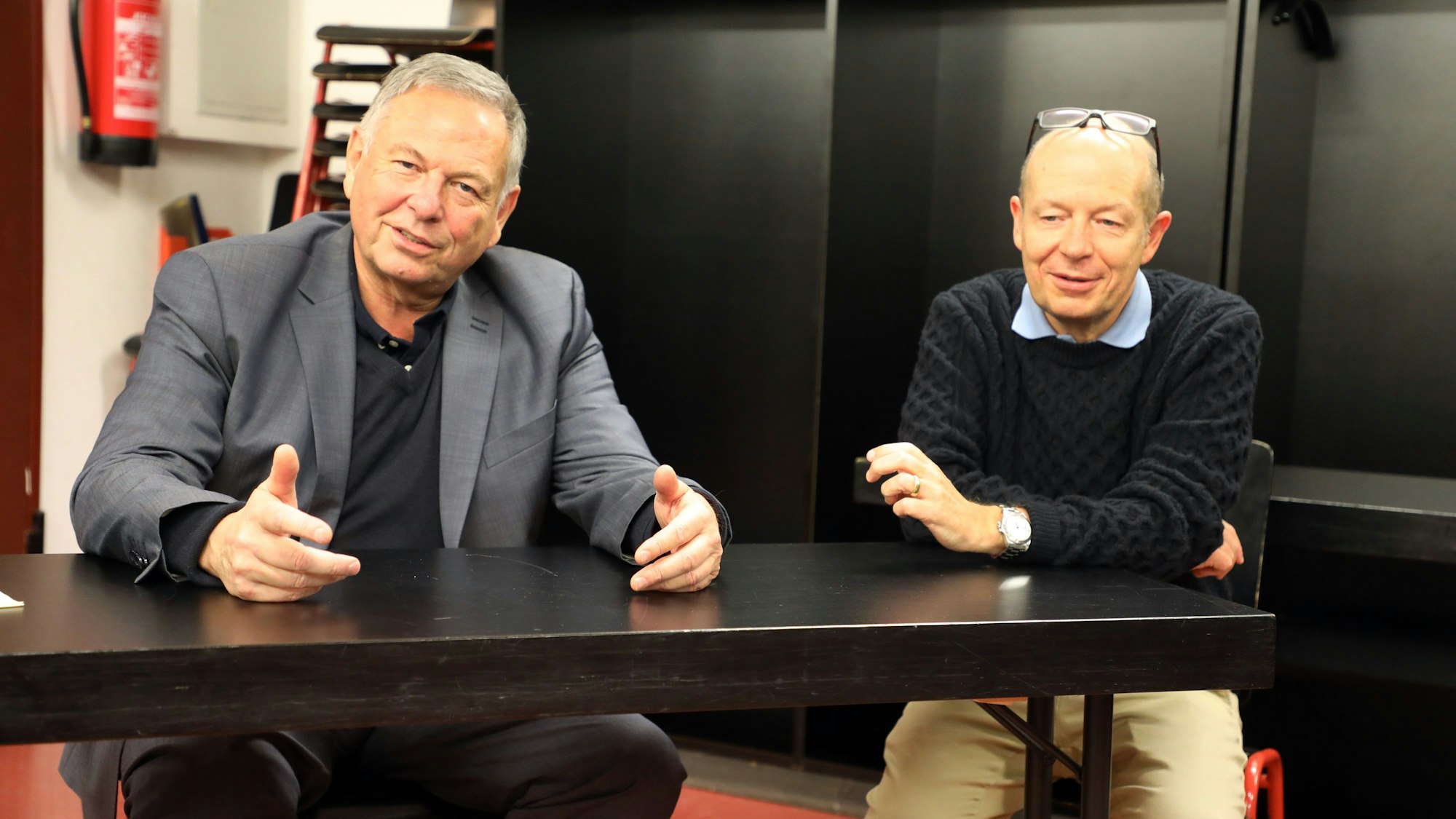 Im Gespräch: Musikalischer Leiter Georg Mais und Löwen-Chef Norbert Pfennings sitzen an einem Tisch, gestikulieren und reden.