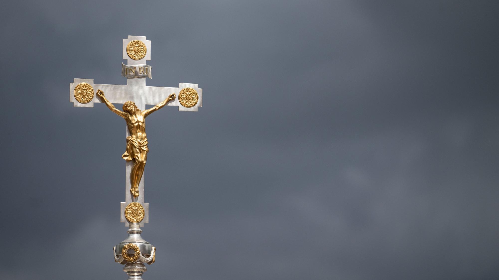 Ein Kruzifix ist beim Schlussgottesdienst des 102. Deutschen Katholikentags vor dunklen Wolken zu sehen.