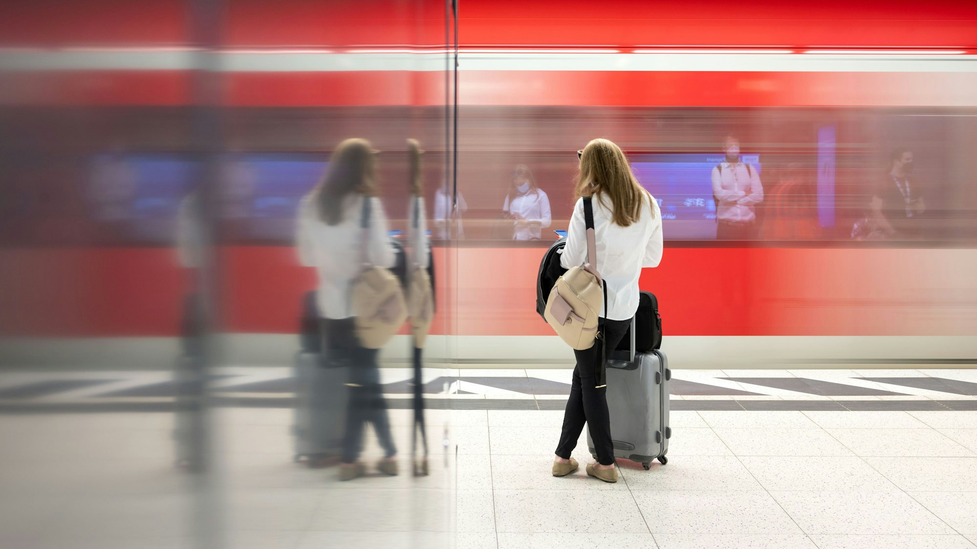 Eine Frau steht an einem Gleis vor einer S-Bahn.