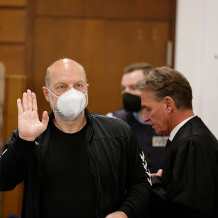 26.04.2022, Nordrhein-Westfalen, Köln: Der Angeklagte Thomas Drach (l) hebt im Kölner Landgericht neben seinem Anwalt Andreas Kerkhof seine Hand zum Gruß.