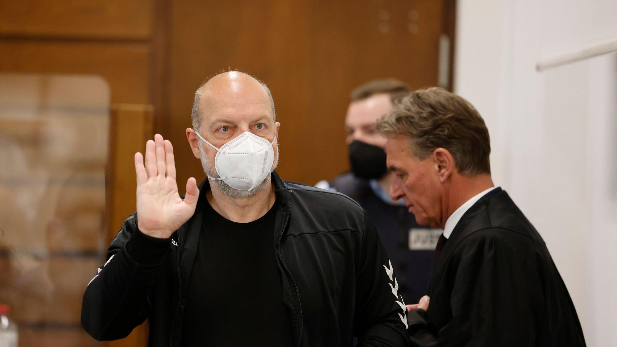 26.04.2022, Nordrhein-Westfalen, Köln: Der Angeklagte Thomas Drach (l) hebt im Kölner Landgericht neben seinem Anwalt Andreas Kerkhof seine Hand zum Gruß.