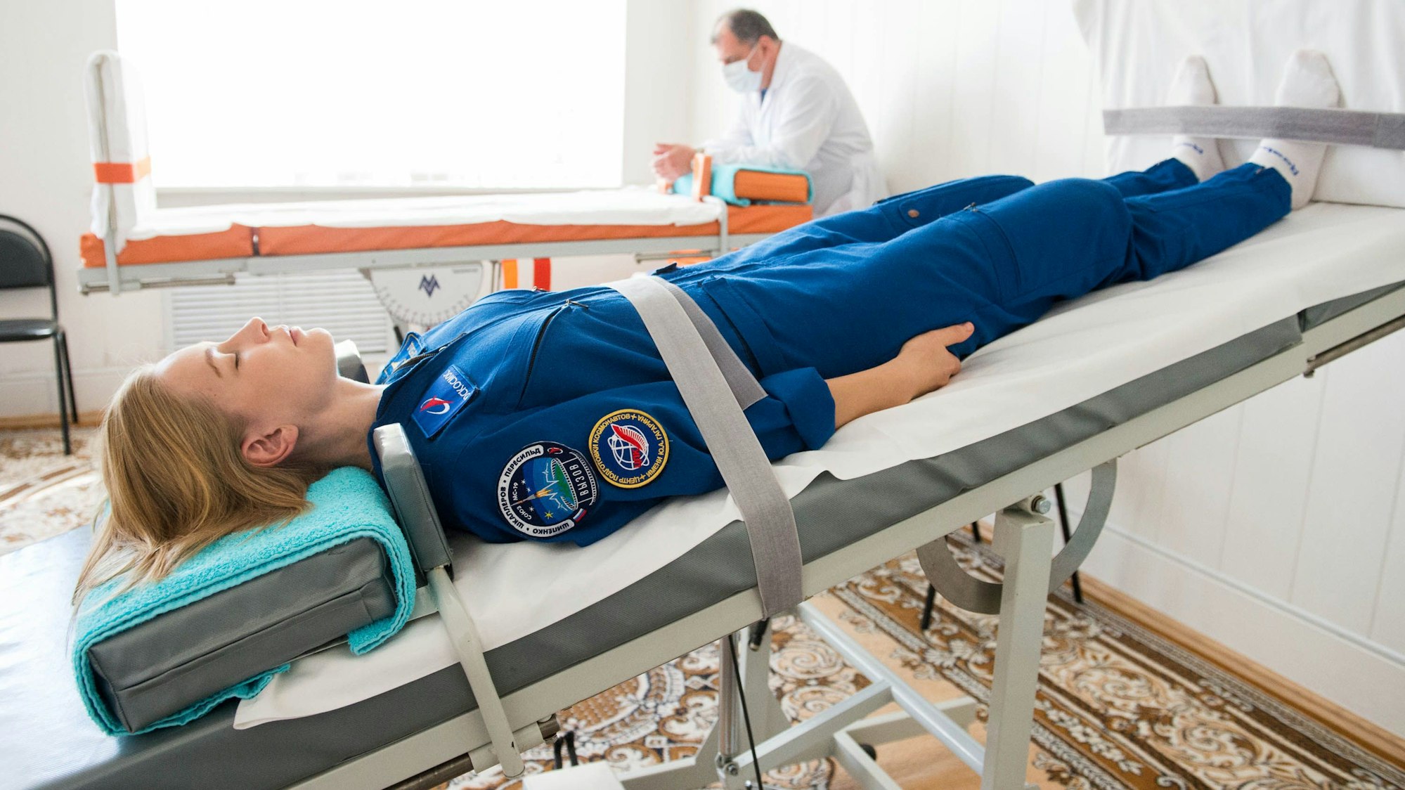 Eine Frau liegt auf einem Bett, mit dem Kopf um mehrere Grad nach unten geneigt.