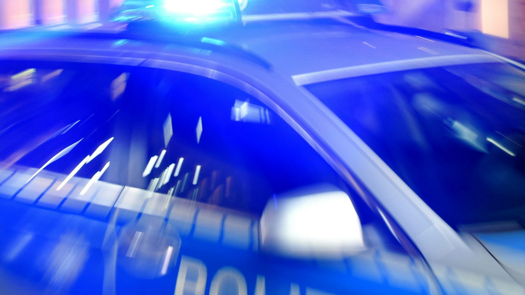 ARCHIV - 06.08.2015, Schleswig-Holstein, Flensburg: ILLUSTRATION - Ein Streifenwagen der Polizei steht mit eingeschaltetem Blaulicht auf der Strasse.