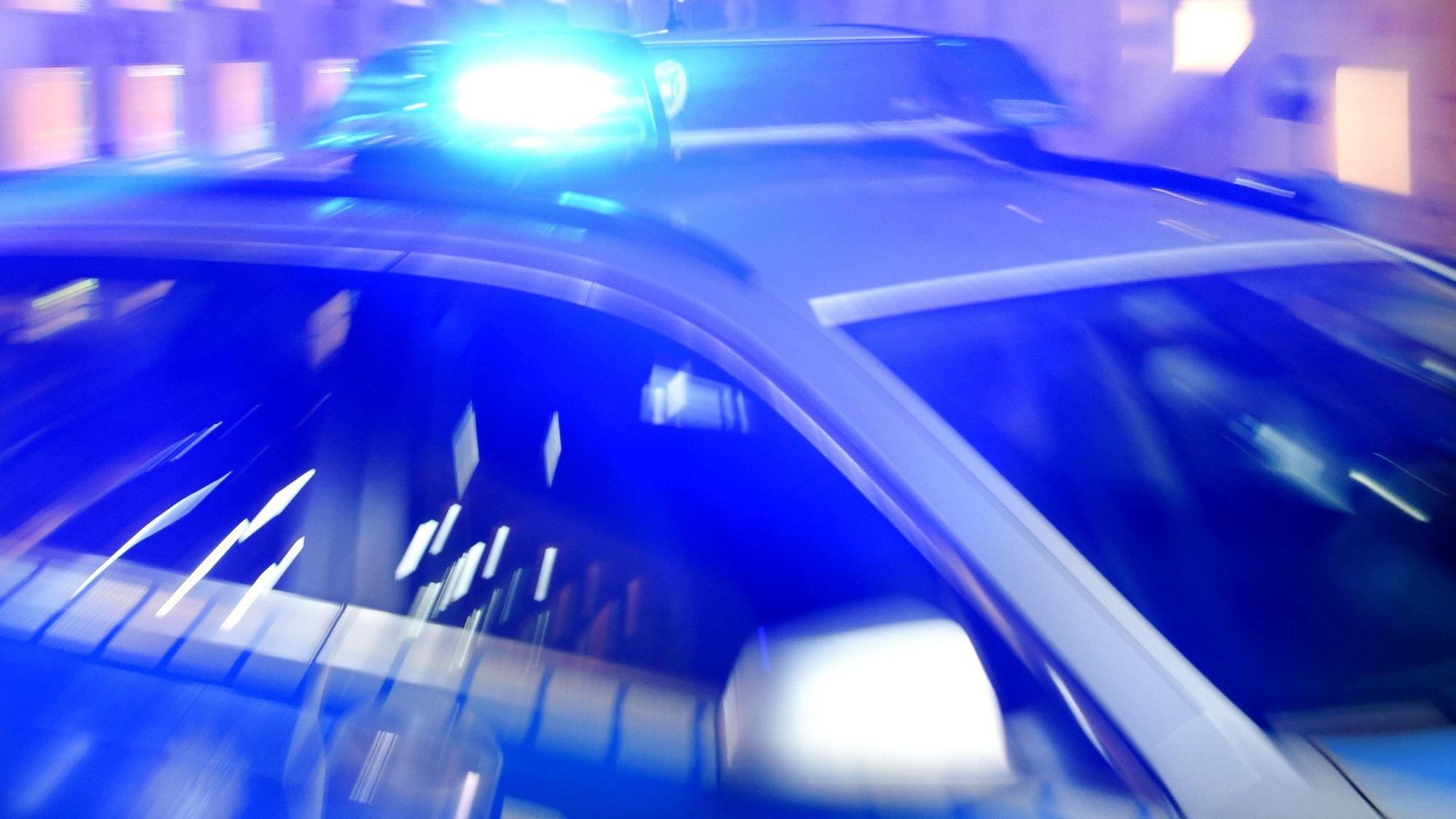 Ein Streifenwagen der Polizei steht mit eingeschaltetem Blaulicht auf der Straße.