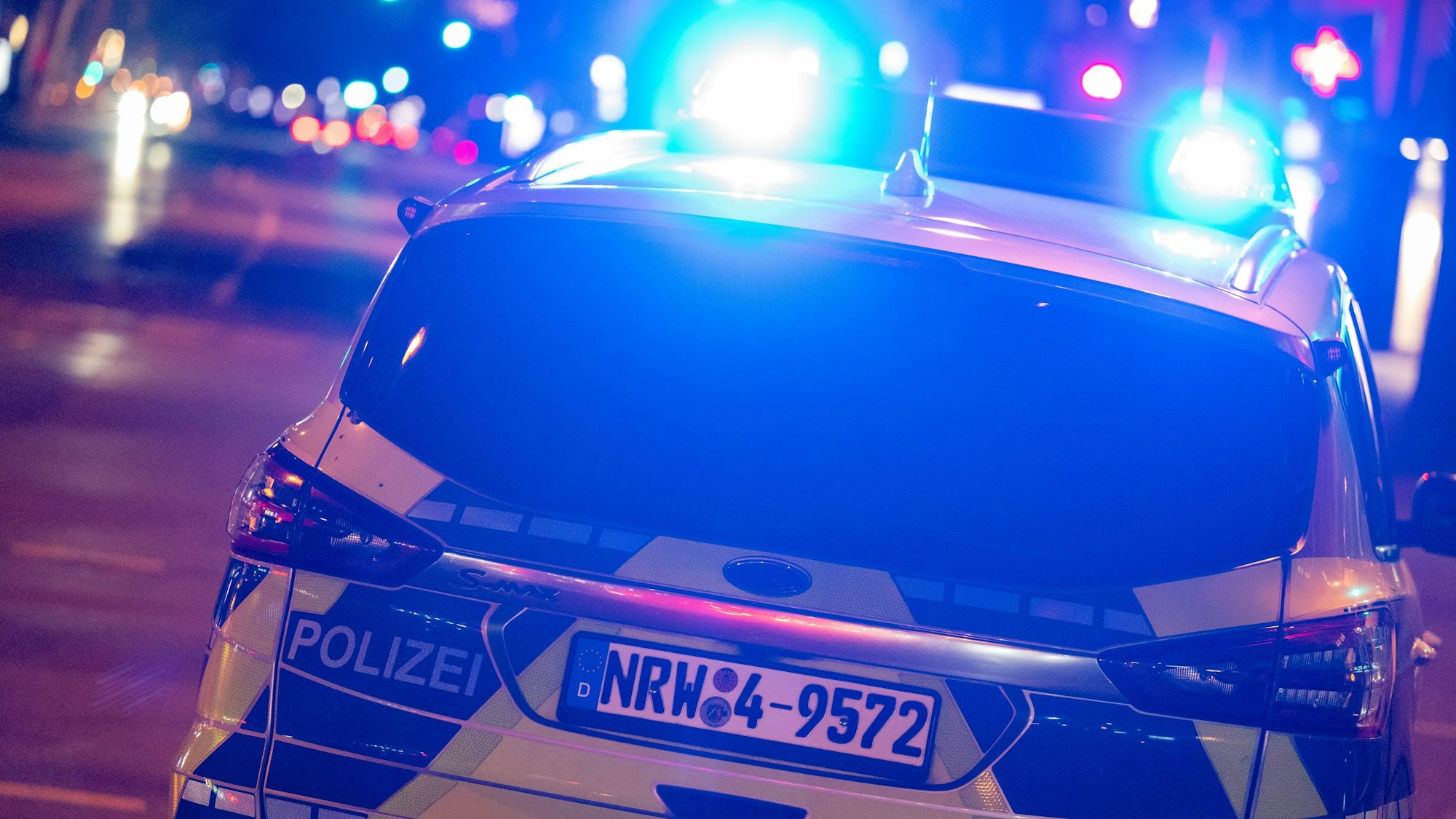 Ein Polizeiauto nachts mit Blaulicht im Einsatz.