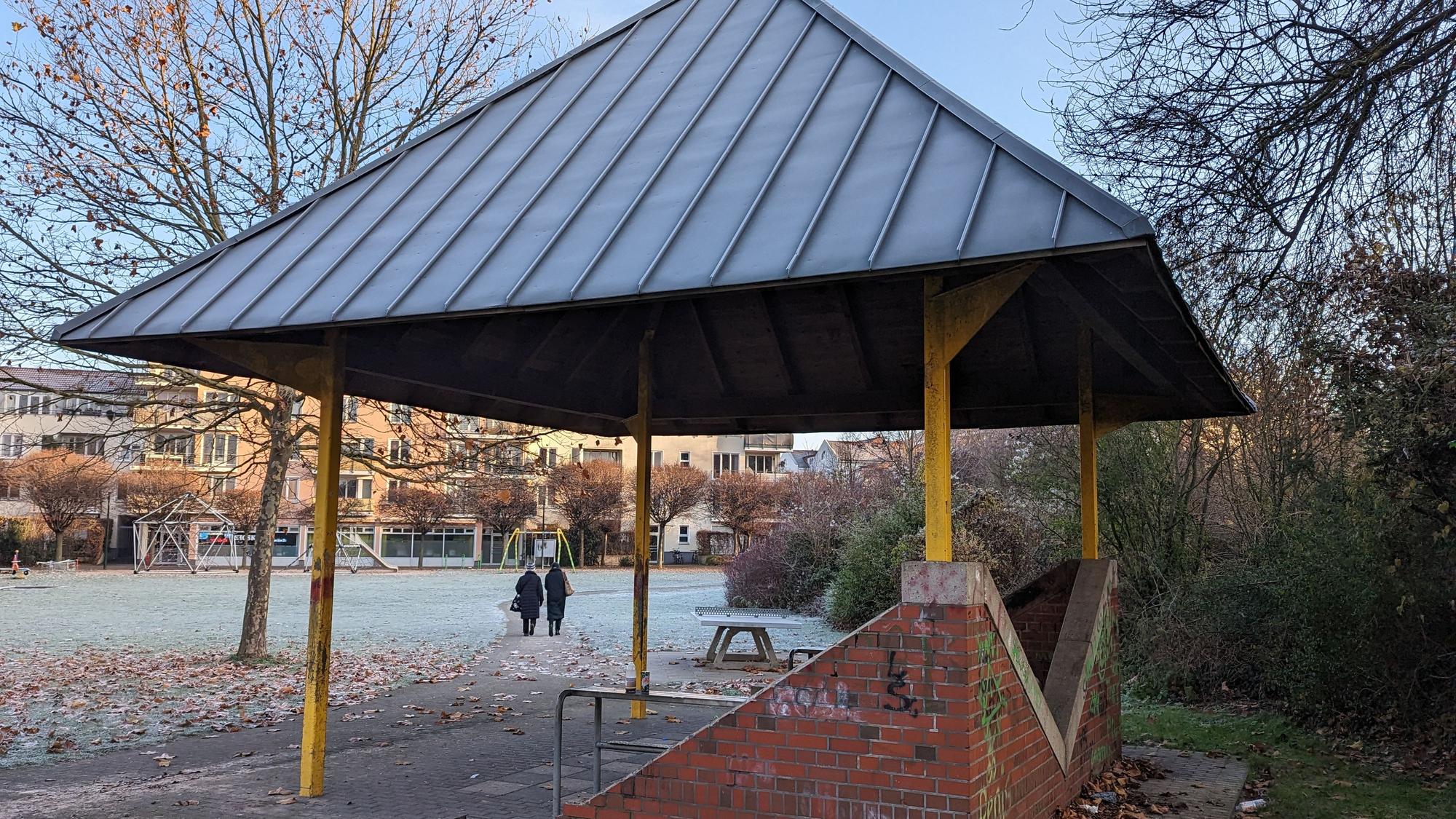 Ein Pavillon steht im Hof. Hinten laufen zwei Frauen.
