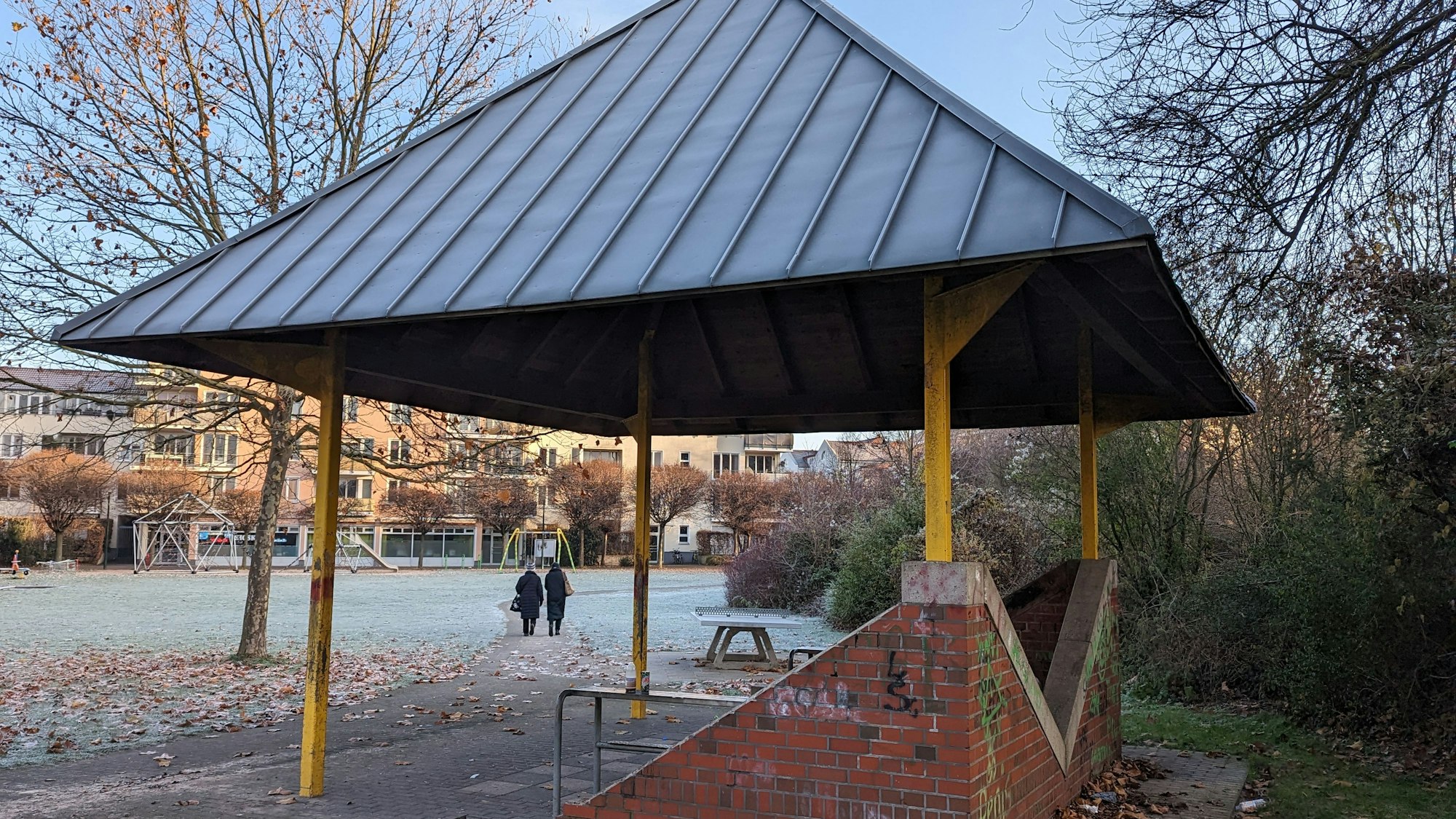 Ein Pavillon steht im Hof. Hinten laufen zwei Frauen.