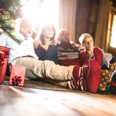 Eine Familie sitzt mit Wintersocken neben dem Weihnachtsbaum.