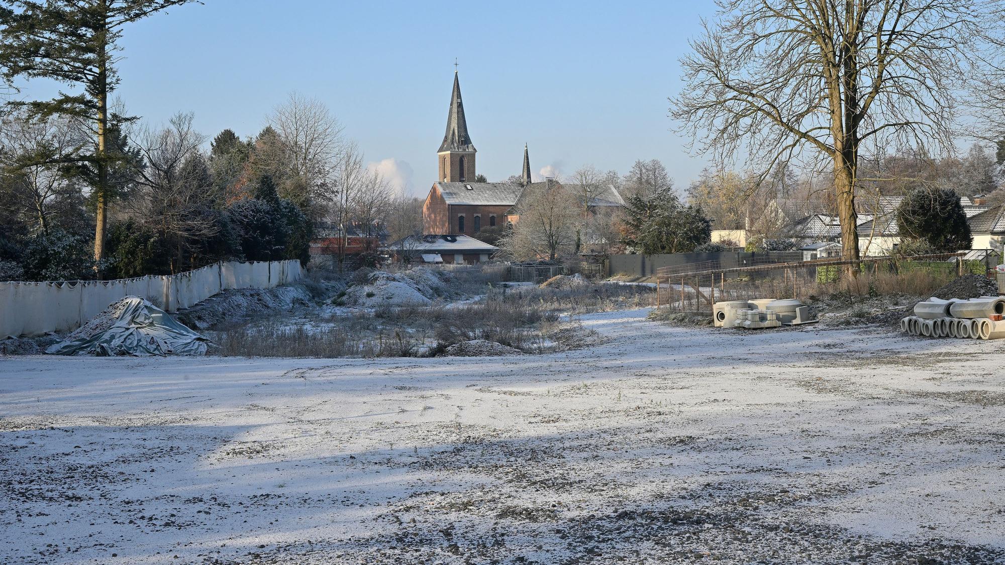 Das Baugrundstück im Schnee, im Hintergrund die Kirche.