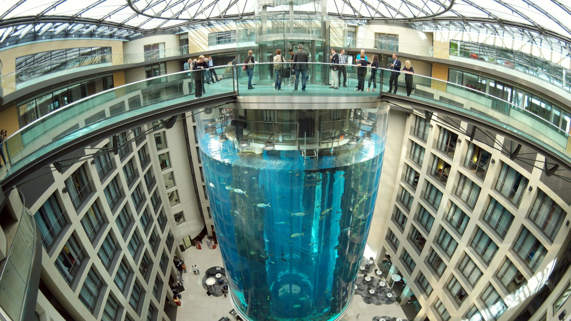 Blick auf den AquaDom als er noch nicht geplatzt war. Es ist ein großer Zylinder in der Mitte eines Hotels. Oben drüber ist eine Brücke, die zu dem Aufzug im Aquarium führen.