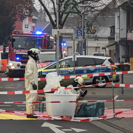 Sondereinsatzkräfte der Feuerwehr arbeiten in kompletter Ausrüstung in einem abgesperrten Bereich.