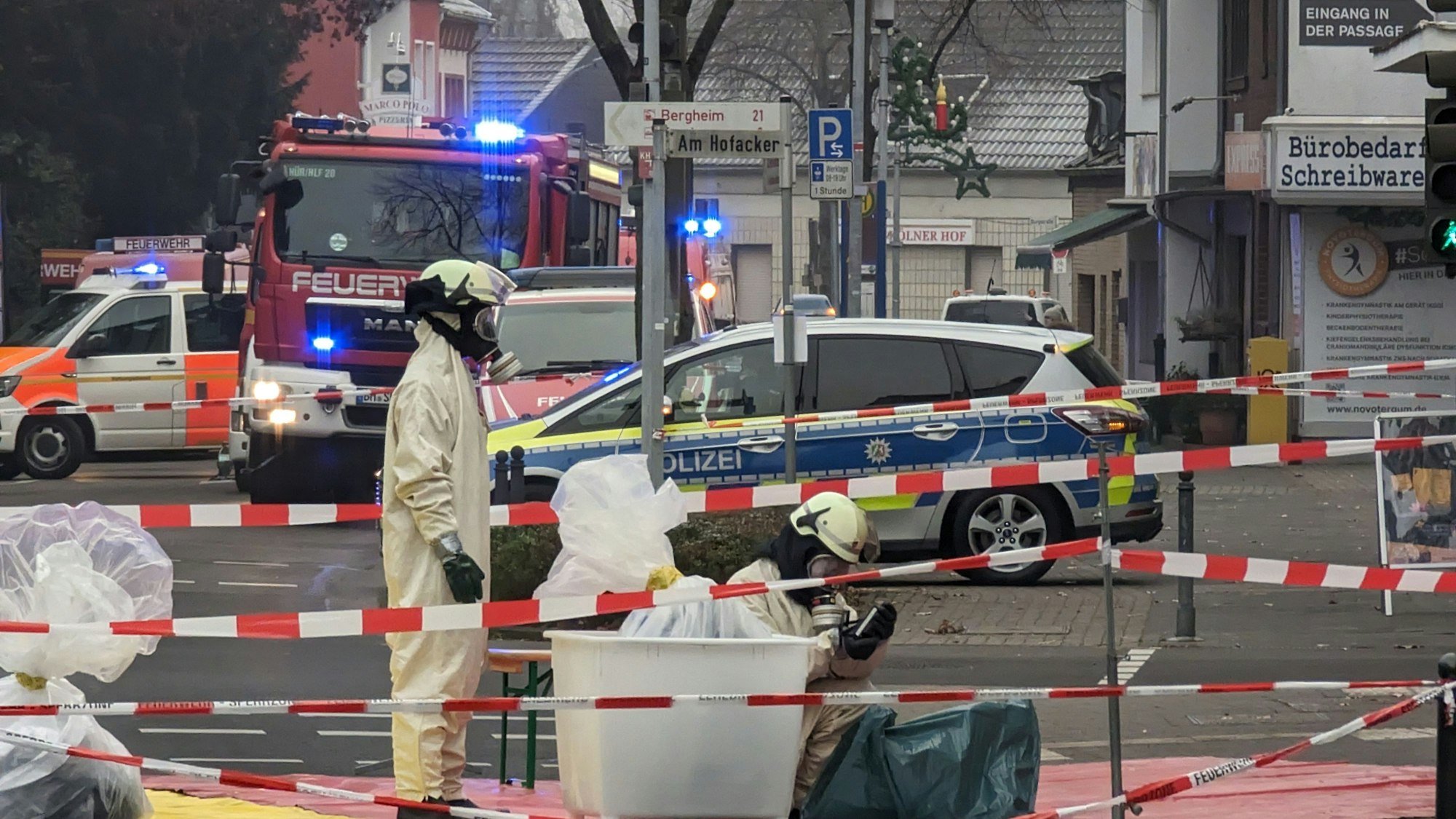 Sondereinsatzkräfte der Feuerwehr arbeiten in kompletter Ausrüstung in einem abgesperrten Bereich.