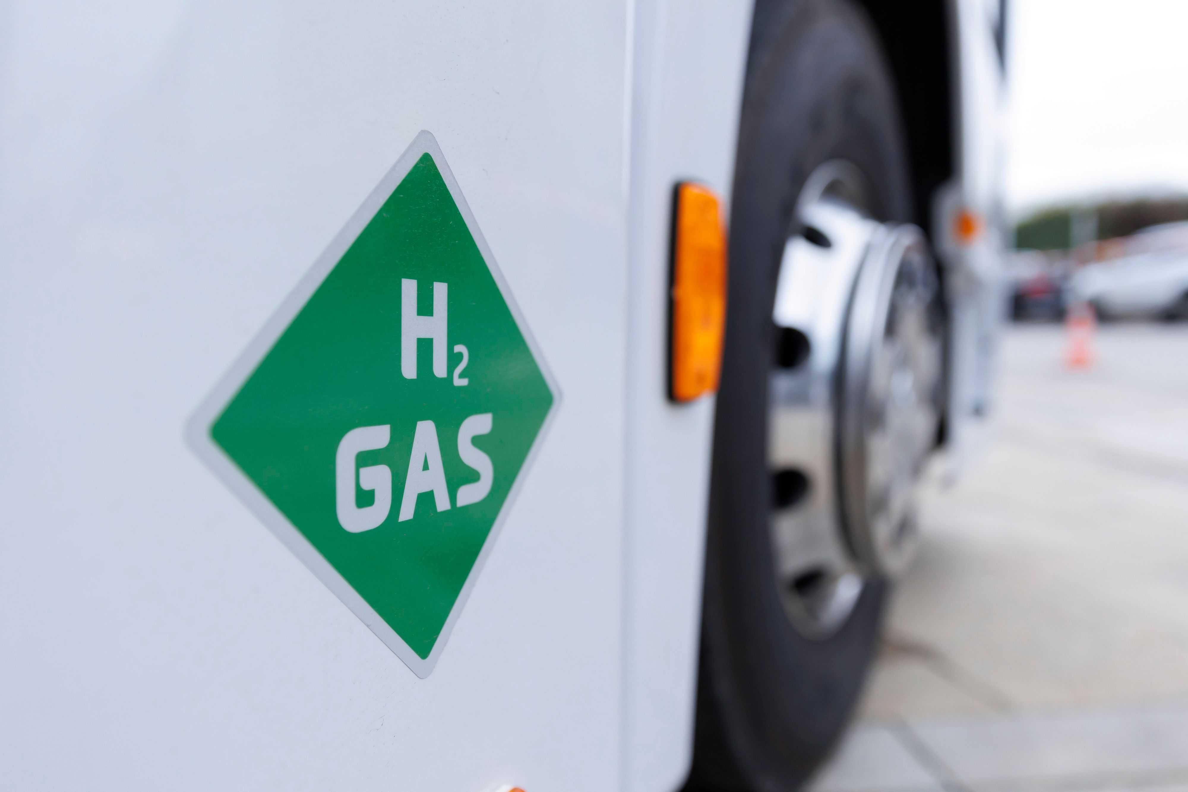 Auf einem weißen Lkw klebt ein grüner viereckiger Aufkleber, auf dem H2 Gas steht.