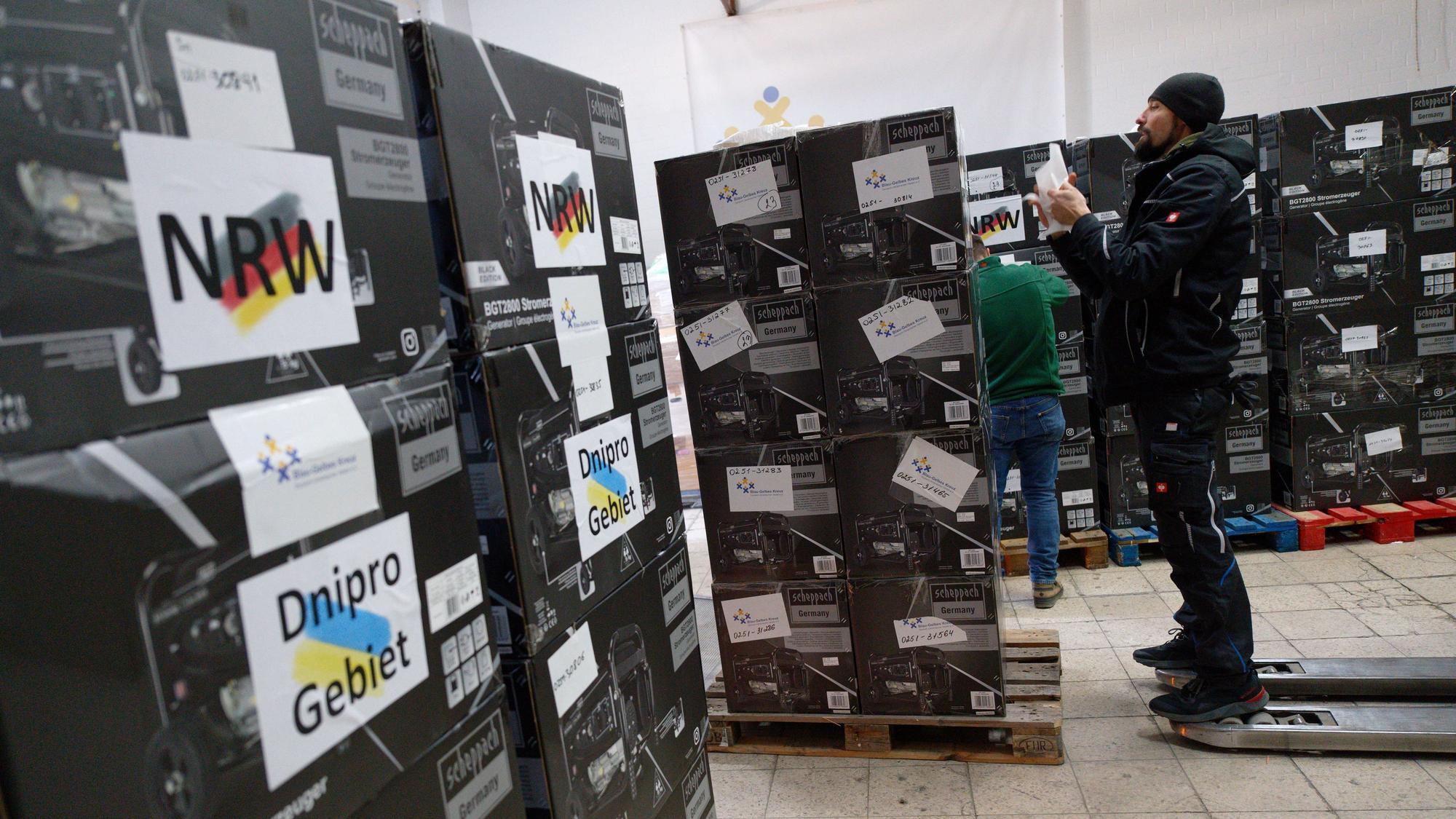 Mitarbeiter bereiten im Spendenlager der Organisation Blau-Gelbes Kreuz Paletten mit Stromgeneratoren für den Transport vor.