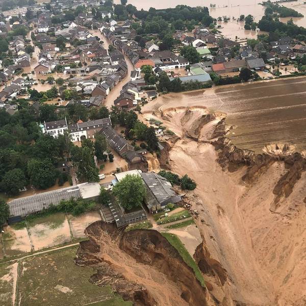 Das Wasser steht in Erftstadt-Blessem in den Straßen. Schlamm fließt an der Abbruchkante der Kiesgrube runter.