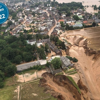Das Wasser steht in Erftstadt-Blessem in den Straßen. Schlamm fließt an der Abbruchkante der Kiesgrube runter.