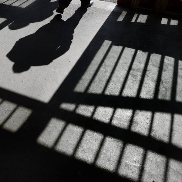 Es sind der Schatten von einem Mensch und von Gitterstäben zu sehen.