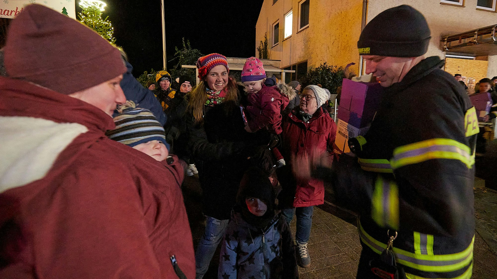 Ein Feuerwehrmann steht bei Besuchern des Lichterzugs.