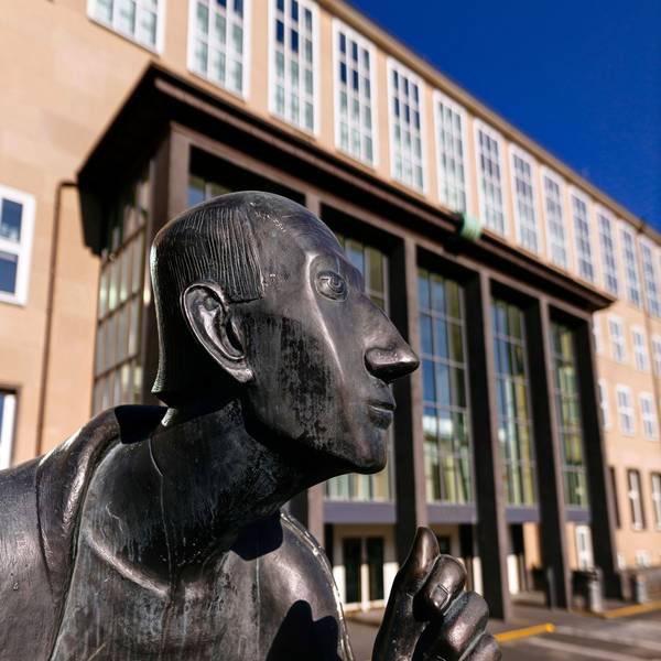 Im Vordergrund der Kopf der Statue von Albertus Magnus, im Hintergrund sieht man das Hauptgebäude der Universität zu Köln.