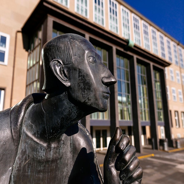Im Vordergrund der Kopf der Statue von Albertus Magnus, im Hintergrund sieht man das Hauptgebäude der Universität zu Köln.