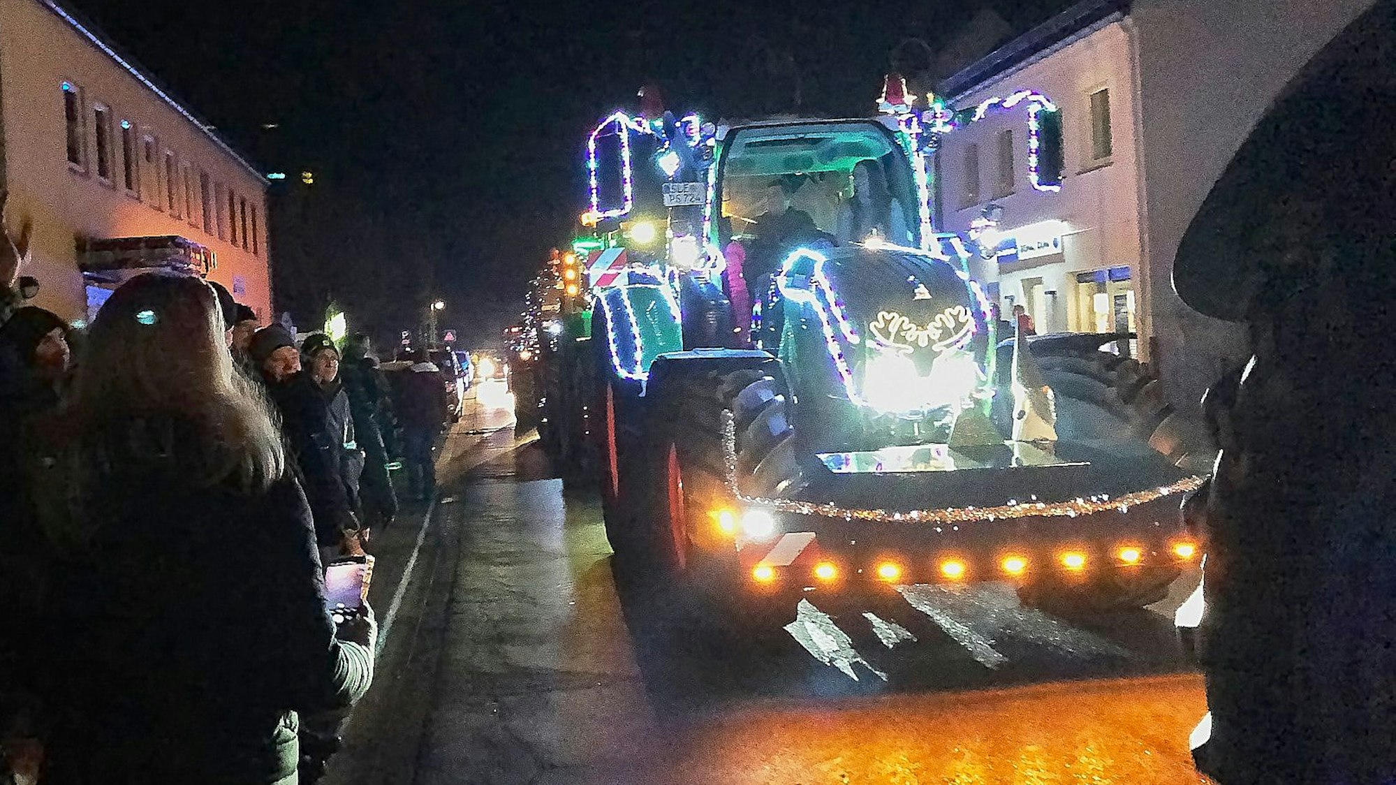 Ein mit Lichterketten geschmückter Traktor fährt durch Kall.
