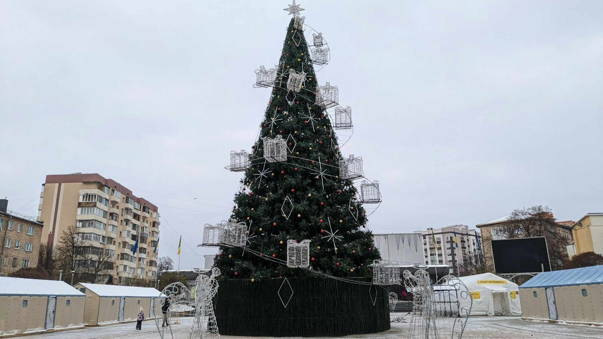 Ein Weihnachtsbaum steht auf einem Platz zwischen Zelten.