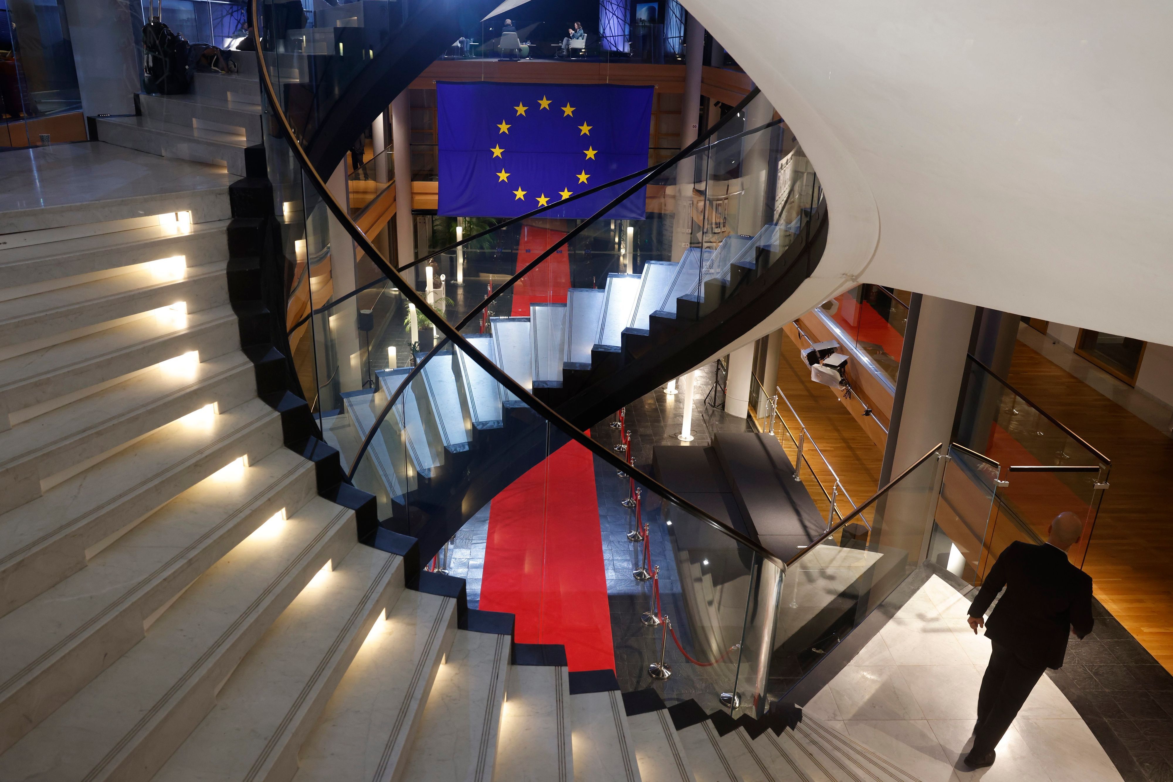 Ein Mann läuft eine Treppe im EU-Parlament in Straßburg herunter. Zu sehen ist zudem die Flagge der Europäischen Union. (Symbolbild)