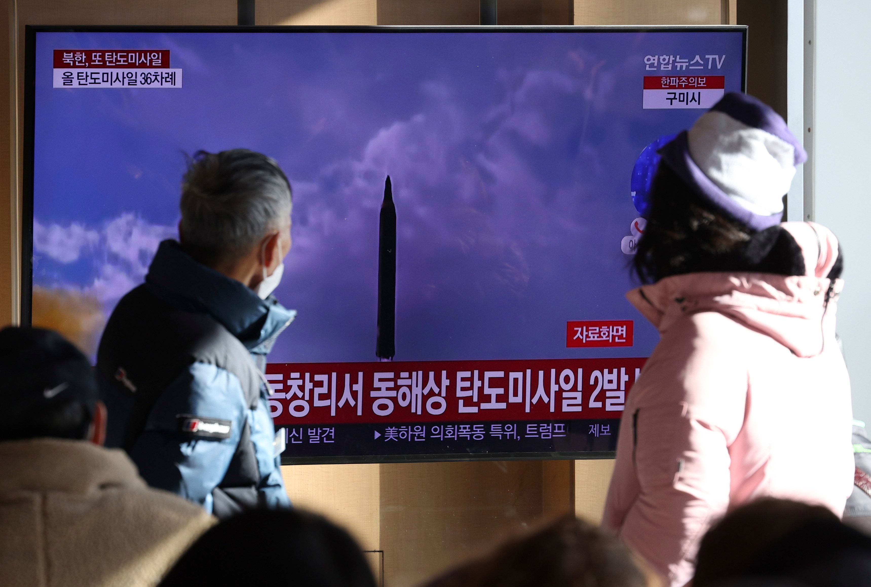 Menschen sehen auf einen Fernsehbildschirm, auf dem eine Nachrichtensendung über den nordkoreanischen Raketenstart mit Filmmaterial gezeigt wird, im Bahnhof von Seoul.