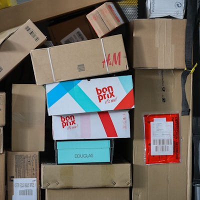 Ein Paketwagen steht voll mit Paketen in einem Zustellpunkt.