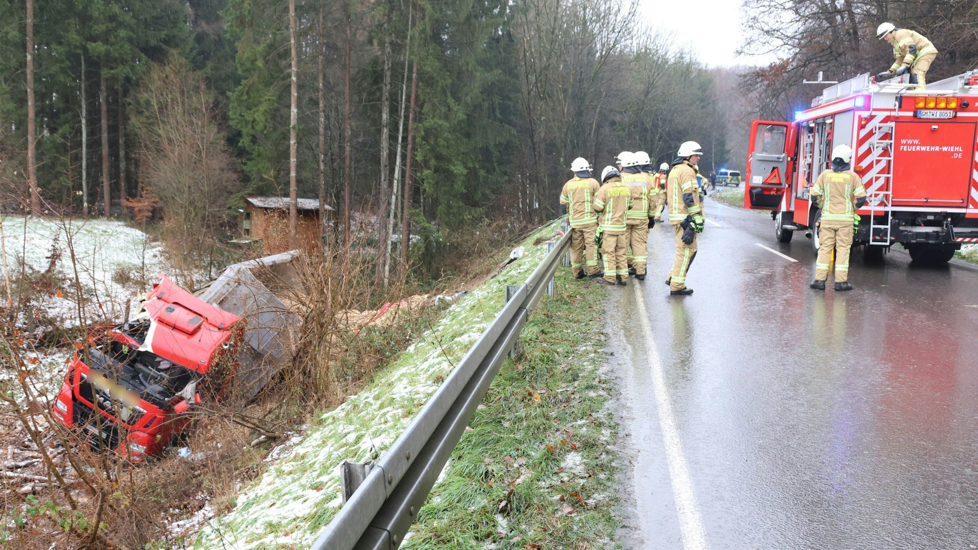Im Graben liegt ein Lkw. Auf der Straße sind mehrere Feuerwehrleute im Einsatz.