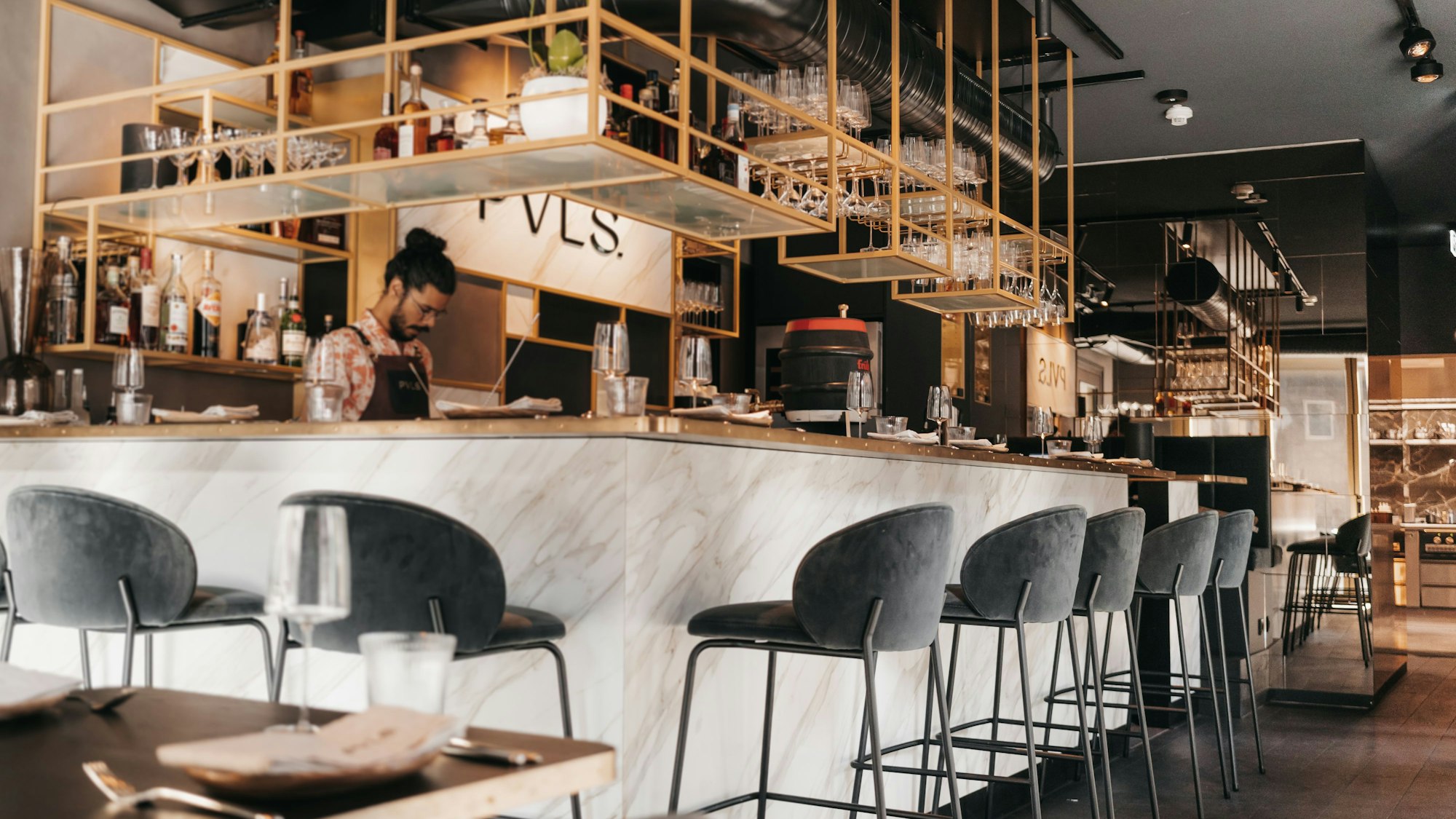 Hohe Stühle stehen aufgereiht vor einer modernen, hell gehaltenen Theke.