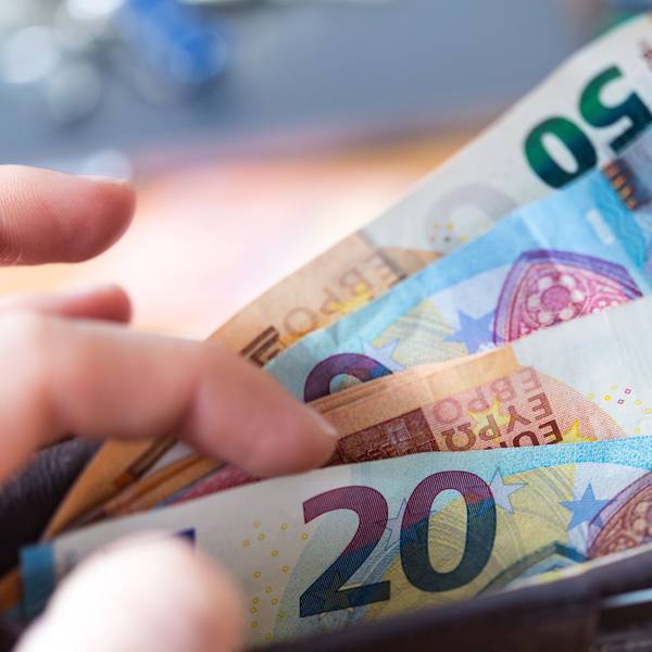 Eine Frau hält eine Geldbörse mit Banknoten in der Hand.