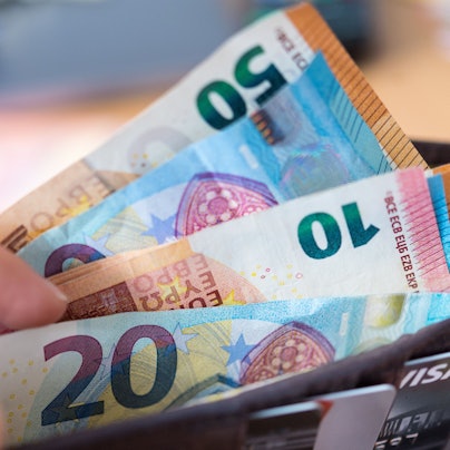 Eine Frau hält eine Geldbörse mit Banknoten in der Hand.