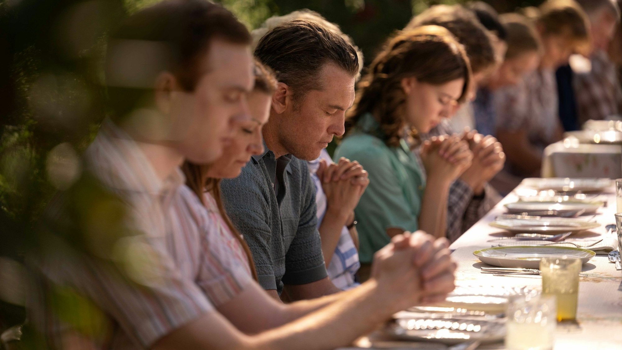 Eine Großfamilie betet am Essenstisch.
